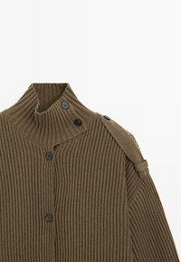 Gerippter olivgrüner Pullover mit hohem Kragen, der auf einer Seite drei schwarze Knöpfe und ein Schulterriemendetail aufweist. Weiche Textur.