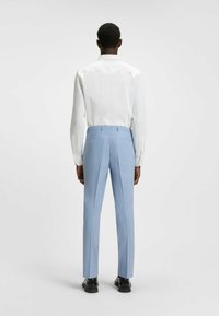 Light blue dress pants with a tailored fit, featuring flat fronts and side pockets, paired with a white long-sleeve shirt.