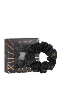 Czarny jedwabny scrunchie o gładkiej fakturze, wyeksponowany na tle czarnego kartonowego pudełka z złotymi akcentami i nazwą marki.