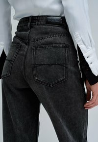 Czarne dżinsy z dobrze widocznym efektem sprania, z wysokim stanem, tylnymi kieszeniami i skórzaną metką z logo na pasku.