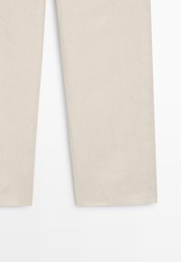 Beige rechte broek, getoond van halverwege het dijbeen naar beneden, met nadruk op de stoftextuur en nette zoom tegen een witte achtergrond.