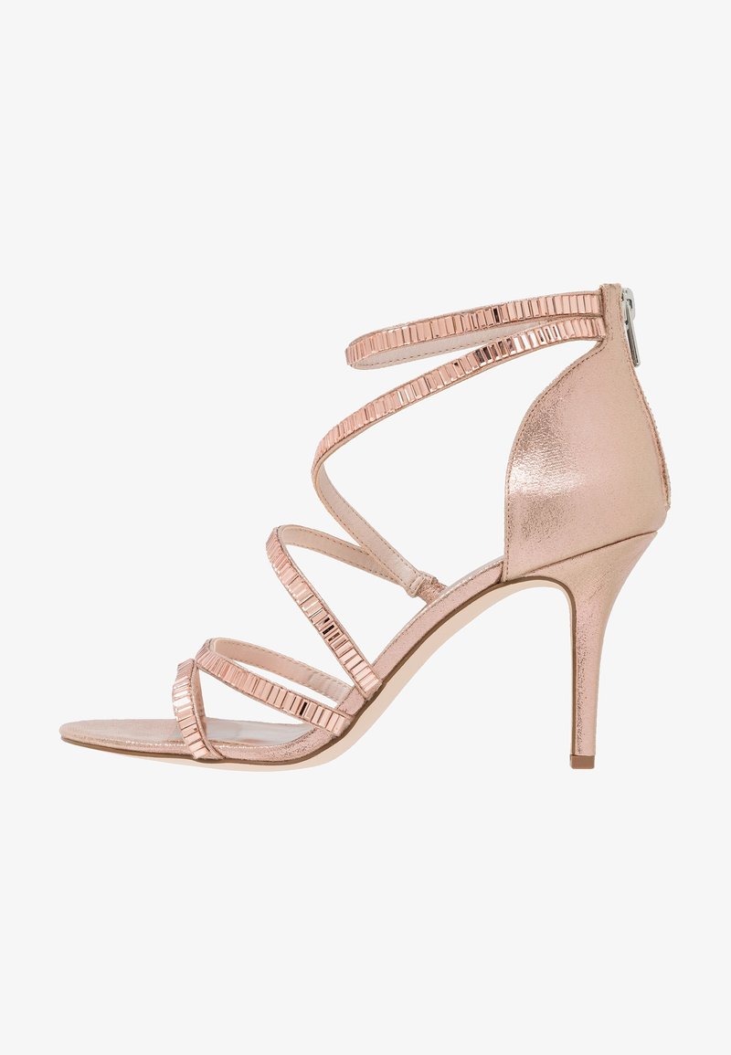Sandale à talons hauts en rose gold avec des brides métalliques, design à bout ouvert et un fin talon aiguille. Accents texturés sur les brides pour plus de détails.