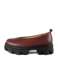 Burgundy leather slip-on shoe with a rounded toe and a chunky black rubber sole featuring textured accents and a subtle heel.