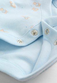 Heled sinise puuvillase kangaga bodi, millel on karu trükk, nööbid ning pehme tekstuur. Sisaldab ümmargust kaelust ja lühikesi varrukaid.