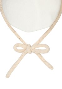 Close-up of a beige knitted string tied in a bow knot at the edge of a white, rounded fabric surface.
