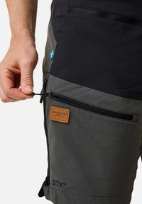 Grijze stoffen shorts met een zwart bovenste gedeelte, voorzien van een ritszak, een leren label en een koord met een togglesysteem voor aanpassingen.