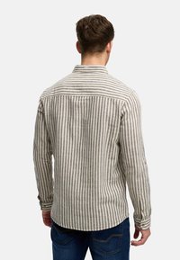 Camicia a maniche lunghe a righe in beige e blu navy, realizzata in un tessuto testurizzato, con colletto a punta e orlo arrotondato.