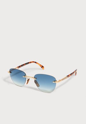 Ochelari de soare fără ramă cu lentile albastre în degrade, punte și brațe metalice aurii, și brațe cu model pentru solzi de broască țestoasă așezate pe o suprafață albă.