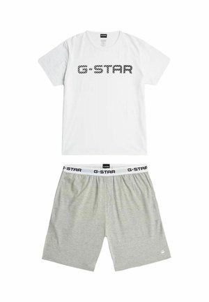 Bílé tričko s krátkým rukávem s černým nápisem "G-STAR" nad světle šedými krátkými kalhotami s bílým pasem zdobeným opakujícím se logem "G-STAR".