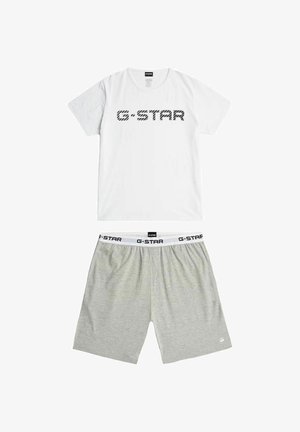 T-shirt bianca a maniche corte con scritta nera "G-STAR" sopra pantaloncini grigio chiaro con fascia bianca in vita con logo "G-STAR" ripetuto.