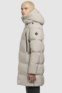 Beige pufferjakke med høj krave, aftagelig hætte, lynlåslommer og et logo patch på ærmet. Glat, quiltet tekstur.