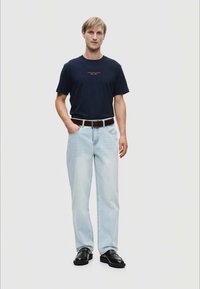 Ναυτικό μπλουζάκι με κείμενο, ανοιχτό μπλε τζιν, καφέ ζώνη και μαύρα παπούτσια. Αθλητική εφαρμογή με κοντά μανίκια και ίσια γραμμή.