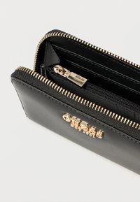 Fekete bőr pénztárca arany színű díszítéssel, cipzáras záródással, több kártyatartó hellyel és egy kis érméknek szánt rekesszel. Texturált belsővel.
