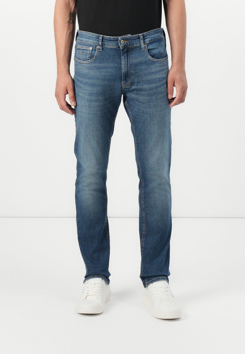 Light blue denim jeans with a slim fit, five-pocket design, and subtle fading. Features a button closure and a small brand patch on the pocket.
