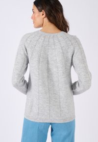 Suéter de punto gris con un diseño acanalado, que presenta líneas verticales y un cuello redondo. La textura suave y las mangas ajustadas realzan su forma.