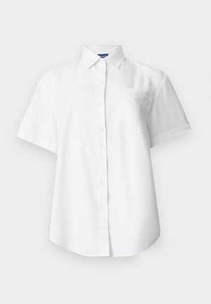 Cămașă albă cu mâneci scurte, cu nasturi, guler și buzunar la piept, expusă pe un fundal deschis și simplu.