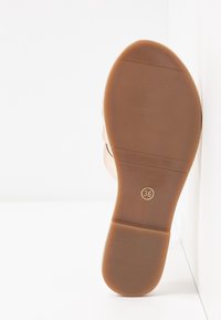 Semelle d'une chaussure marron clair de taille 36, présentant un profil texturé lisse, reposant contre une surface blanche.