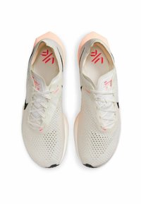 Białe siateczkowe buty do biegania z różowymi akcentami i czarnymi detalami, charakteryzujące się aerodynamiczną sylwetką, cienkimi sznurówkami i amortyzowaną podeszwą.