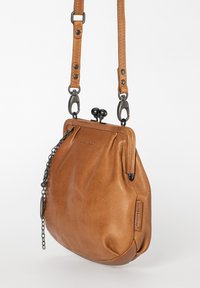 Brown leather crossbody bag with black metal clasp, adjustable strap, and a decorative black chain detail hanging on the side.