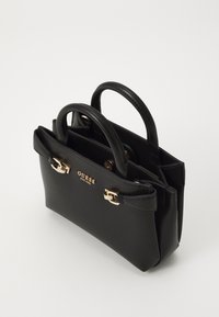 Black leather handbag with dual handles, featuring gold hardware accents and a prominent logo. Compact rectangular shape with smooth texture.