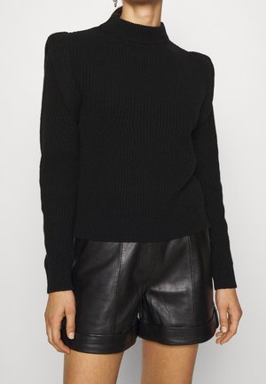 Black ribbed knit sweater with a high neck, featuring long sleeves and a fitted waist, paired with high-waisted black leather shorts.