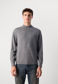 Pelēks garām piedurknēm turtlenecks džemperis, mīksta tekstūra, pieguļošs dizains, ribotās aproces, bez redzamām rakstiem, saskaņots ar ziliem džinsiem.