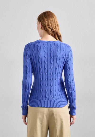 Sinine kaelusete kudum, millel on soonikkoesäär ja -varrukad, millel on tekstuuriline muster, nii et see sobib keha külge ja ümar kaelus.