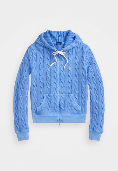 Šviesiai mėlynas užtrauktuku užsegamas džemperis, pagamintas iš tekstūruoto kabelinio mezginio. Yra su reguliuojamu gaubtu, priekinėmis kišenėmis ir raištiniais rankogaliais bei apačia.