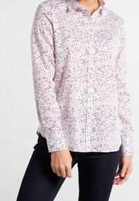 Camicia button-up in tessuto bianco con un motivo a pois colorato in rosso, rosa e nero. Presenta maniche lunghe e un colletto classico.