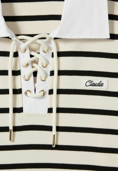 Polo a righe con linee orizzontali bianche e nere, colletto bianco e lacci frontali con occhielli dorati. Logo "Claudie" ricamato.