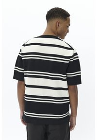 Pull à manches courtes noir et blanc à rayures, en tissu tricoté texturé, avec un col rond et une coupe décontractée.