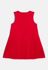 Κόκκινο φόρεμα χωρίς μανίκια με φερμουάρ στην πλάτη, φαρδιά γραμμή και αντίθετη ριγέ φόδρα στα ανοίγματα των χεριών. Λείο ύφασμα, χωρίς ορατά σχέδια.