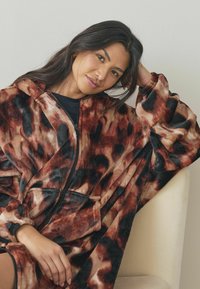 Fleece oversized hoodie in bruin en zwart dierenprint, met ritsluiting en zijzakken. Zachte textuur met een relaxte pasvorm.