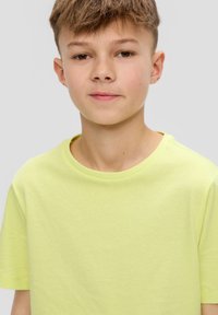 Svěže zelené tričko s krátkým rukávem vyrobené z měkké bavlny, s kulatým výstřihem a hladkým povrchem. Žádné viditelné vzory ani kovové detaily.