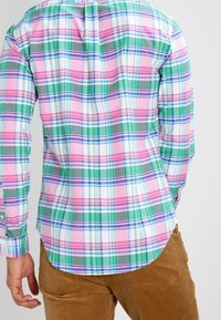 Långärmad skjorta med knappar, med ett livfullt rutmönster i rosa, grönt och blått, med en rundad fåll och kontrasterande krage.