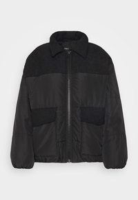 Doudoune noire avec une fermeture éclair frontale, deux poches avant avec rabats, un panneau côtelé aux épaules et des couvre-poches, ainsi qu'un large col.