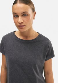 Camiseta de manga corta gris oscuro con cuello redondo, hecha de una tela suave, presenta una textura sutil y un corte holgado.