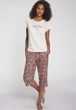 Cotton t-shirt in cream with "Wild at Heart" printed in black. Patterned cropped pants in red and beige wavy stripes with an elastic waistband.