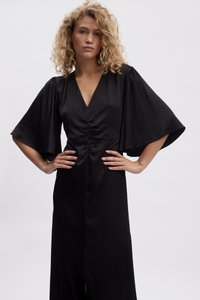 Black dress with a V-neck and gathered center, featuring wide, flowing sleeves and a long, smooth silhouette. Elegant and minimal design.