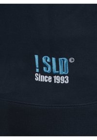 Sötétkék pulóver, hímzett szöveggel: "!SLD" világoskékkel és "Since 1993" fehérrel. Sima textúra ribbelt aljjal.