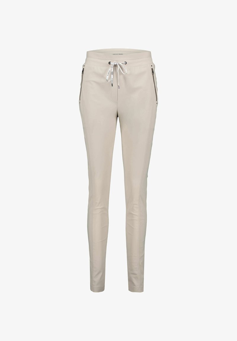 Pantalones color beige claro hechos de material suave, con cintura elástica ajustable, dos bolsillos con cremallera en la parte frontal y un corte ajustado.