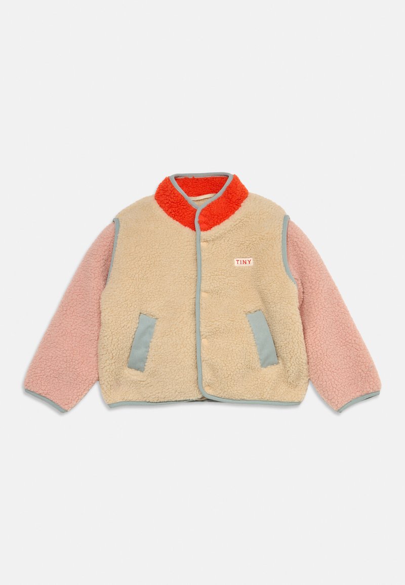 Veste polaire enfant avec corps beige, manches roses, col rouge, deux poches avant et étiquette "TINY" sur la poitrine.