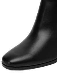 Čierna kožená členková čižma s špicatou špičkou, hladkou textúrou a minimalistickým dizajnom. Podrážka je plochá a má nízky profil.