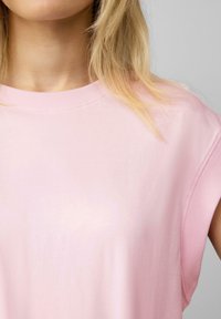 Roze katoenen t-shirt met een ronde halslijn en korte, opgerolde mouwen. De stof heeft een gladde textuur en een casual pasvorm.