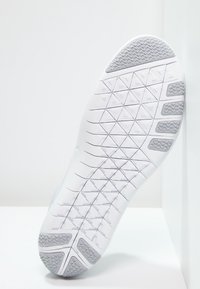 Biała podeszwa sportowego buta z teksturowanej gumowej powierzchni, posiadająca geometryczny wzór, w tym akcenty w kształcie trójkątów i prostokątów.