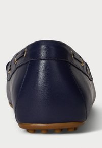 Tengerészeti bőr slip-on cipő lekerekített formával, texturált felülettel és aranyszínű fémrészekkel. Gumitalp kis tüskékkel a tapadás érdekében.