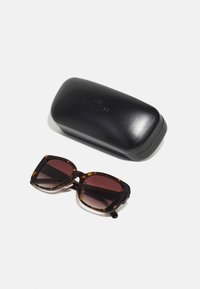 Tortoiseshell sunglasses with square frames and gradient dark lenses, positioned next to a glossy black case featuring embossed logo.
