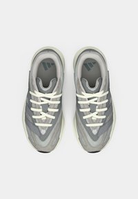 Pilki sportiniai bateliai, pagaminti iš akių tinklo ir sintetinės medžiagos, su baltais nėriniais, trimis šoninėmis juostelėmis ir tekstūruotu padu.