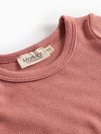Close-up of a ribbed pink baby shirt neckline with a white size 9m MarMar Copenhagen label sewn inside.