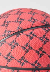 Közeli kép egy texturált narancssárga kosárlabdáról, fekete hálószerű mintákkal és fekete vonalakkal a felületén.